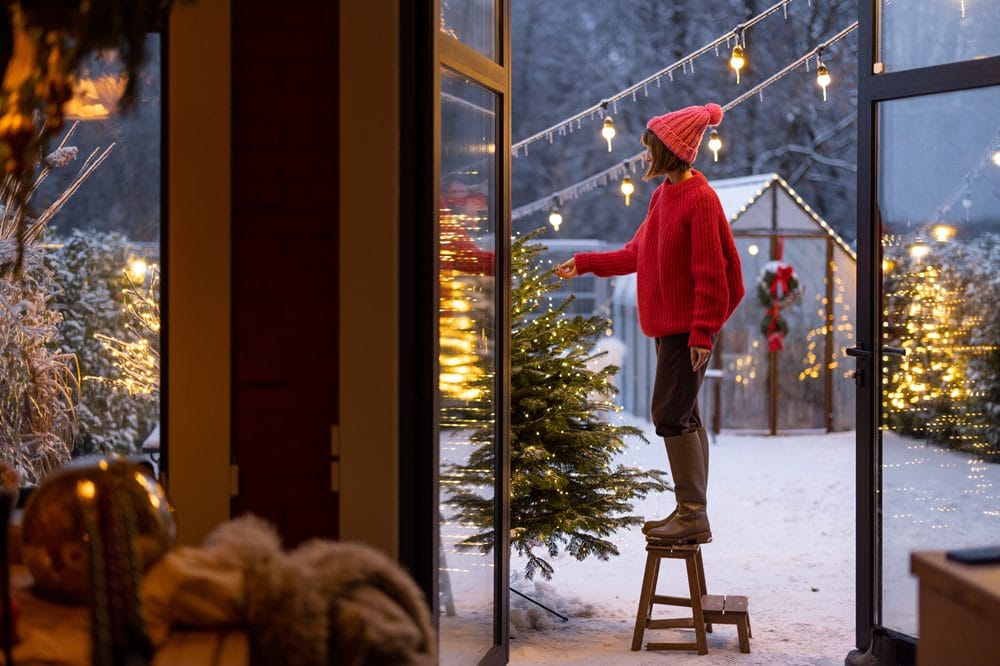 En kvinde pynter sit juletræ i haven
