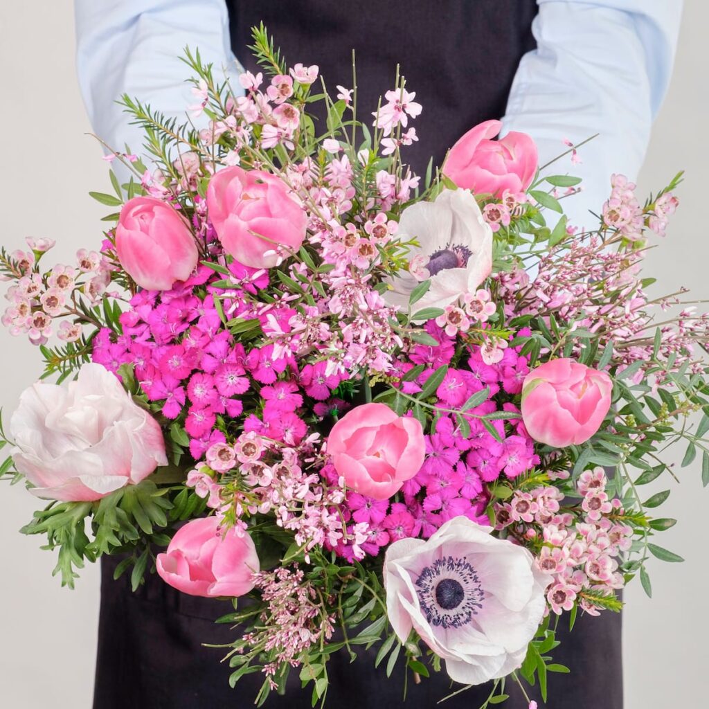 En person holder en stor buket lyserøde blomster.