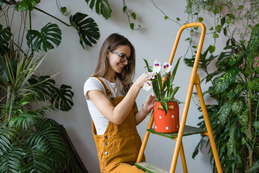 En kvinde passer en orkidé i et rum fuld af planter.