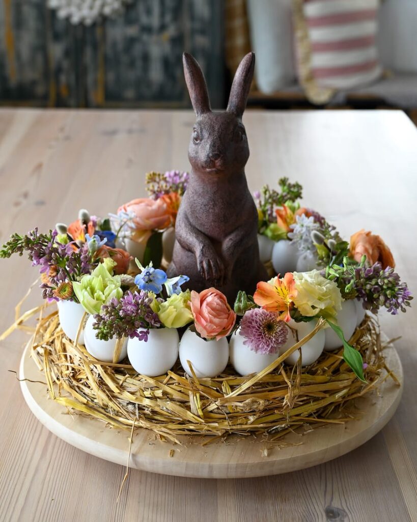 hjemmelavet kreativ krans til påskebordet med æggeskaller og små fine forårsblomster og påskehare i midten