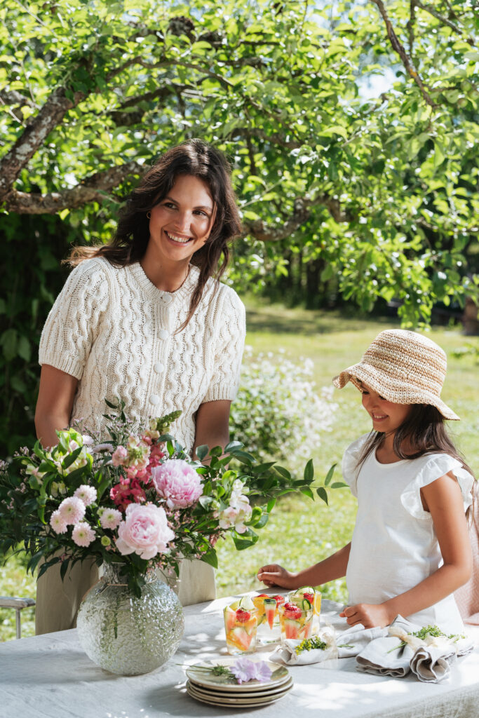 smilende mor og datter med smukke blomster på bord
