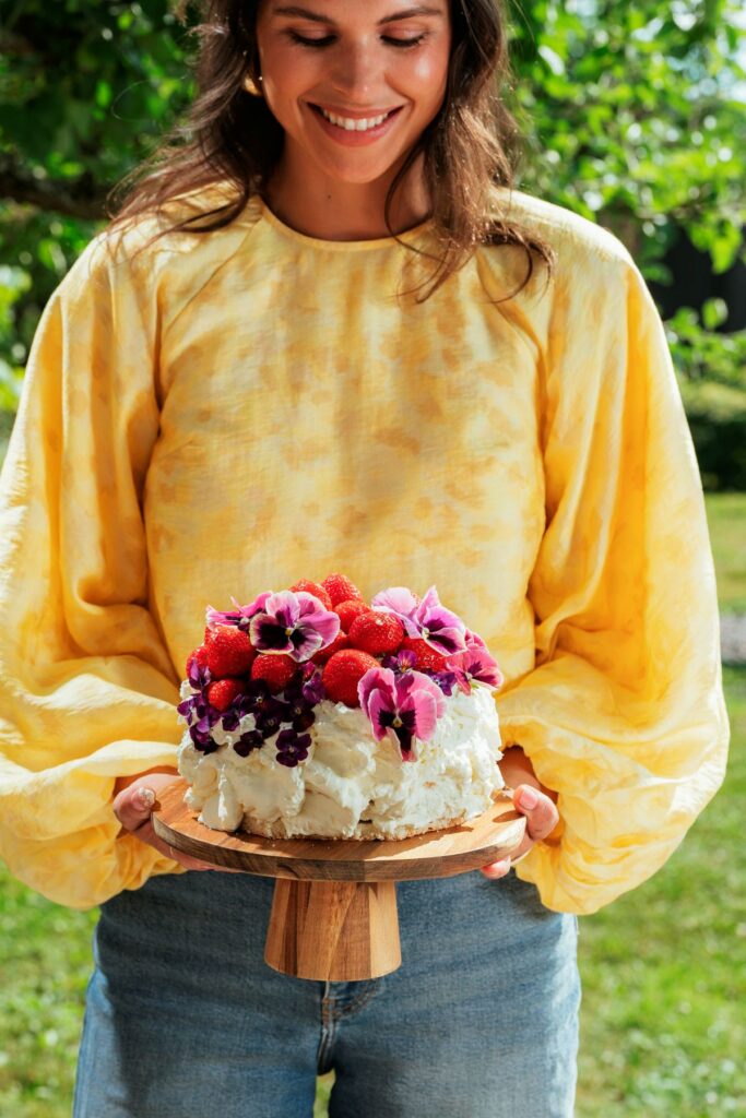Kvinde holder kage dekoreret med blomster og frugter
