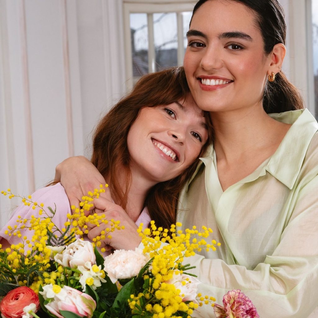 Smilende veninder med en smuk venskabsbuket fra Interflora